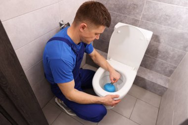 Muslukçu tuvalet tıkanıklığını açıyor, kapalı alanda, üst tarafta.