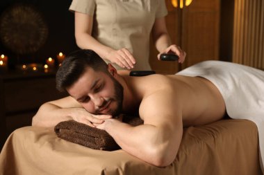 Adam spa salonunda taşlarla masaj yaptırıyor.