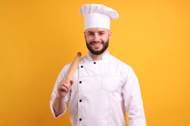 Üniformalı mutlu pastacı turuncu arka planda merdane tutuyor.