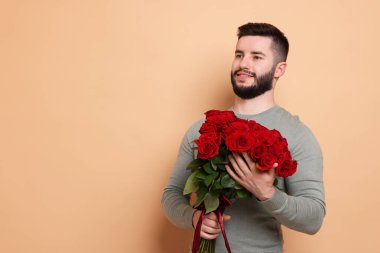 Bej arka planda kırmızı gül buketi olan mutlu adam, metin için boşluk.