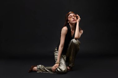 Siyah arka planda şık giyinmiş güzel bir kadının tam boy portresi.