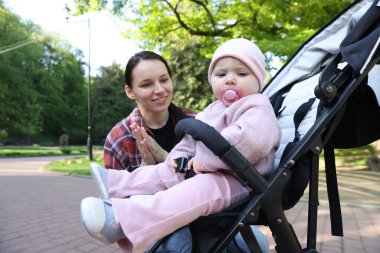 Parkta bebek arabasında sevimli bebeğiyle annesi
