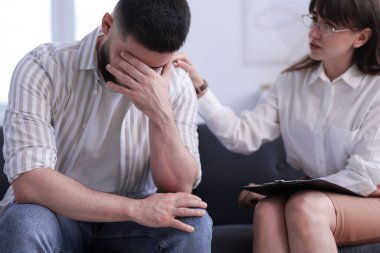 Ofisteki koltukta terapi seansında hastaya destek veren psikolog.