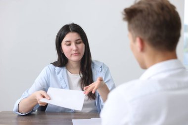 Genç bir kadın içerideki ahşap masadaki adama şikayette bulunuyor.
