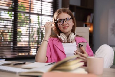 Evde ders çalışırken kulaklık takan genç bir öğrenci.