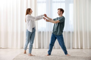 Mutlu genç çift evde dans ediyor.