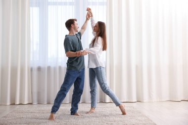 Mutlu genç çift evde dans ediyor.