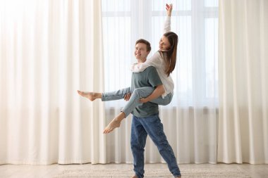 Mutlu genç çift evde dans ediyor.