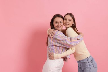 Pembe arkaplanda sarılan arkadaşlar, metin için alan