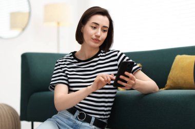 Evde modern akıllı telefon kullanan güzel bir kadın.