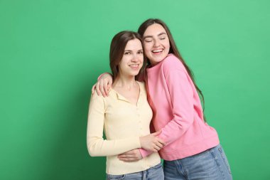 Mutlu arkadaşlar yeşil arka planda birbirlerine sarılıyorlar.