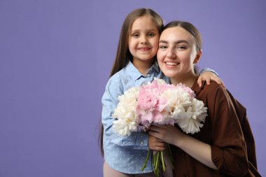 Anne ve kızı mor arka planda bir buket güzel şakayıkla