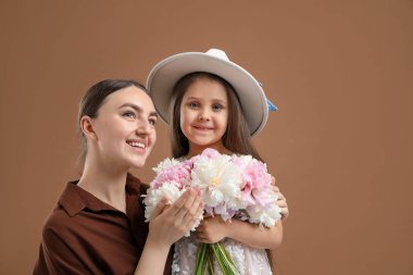 Anne ve kızı kahverengi arka planda bir buket güzel şakayıkla mesajlaşmak için yer açıyorlar.