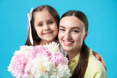 Anne ve kızı açık mavi arka planda bir buket güzel şakayıkla