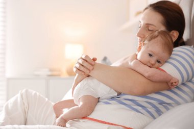 Anne yeni doğmuş bebeğini evde uyutuyor.