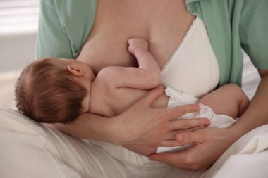 Anne yeni doğmuş bebeğini evde emziriyor.