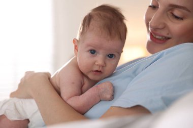 Anne yeni doğmuş bebeğini evde yatırıyor, yakın plan.