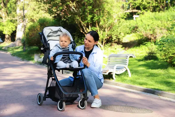 Parkta bebek arabasında sevimli bebeğiyle annesi