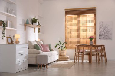 Odada rahat bir kanepe ve sandalyeli şık bir yemek masası. İç tasarım