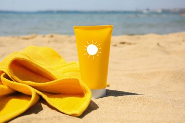 Güneş kremi ve kumsalda havlu. Güneş resimli tüp