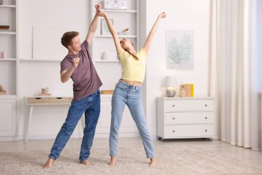 Mutlu genç çift evde dans ediyor.