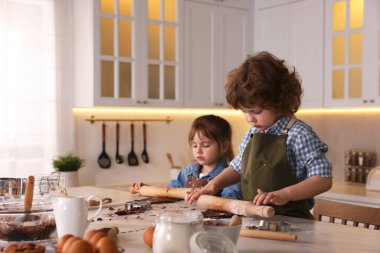 Yemek tarifi. Küçük çocuklar mutfaktaki masada kurabiye yapıyorlar. Metin için boşluk