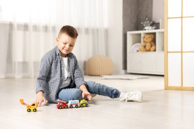 Küçük çocuk evde oyuncak arabalarla oynuyor. Metin için boşluk