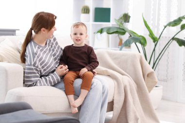 Anne oğluyla evdeki kanepede vakit geçiriyor.