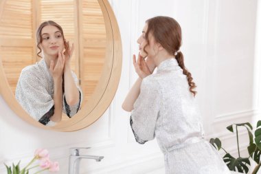 Güzel bir kadın aynada kendine bakıyor.