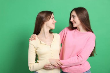 Mutlu arkadaşlar yeşil arka planda birbirlerine sarılıyorlar.