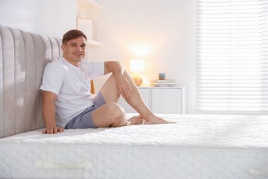 Evdeki yumuşak yatakla yatakta oturan genç adam, mesaj için yer var.