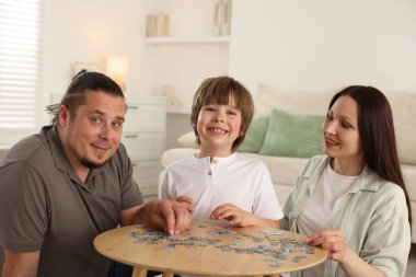 Aileler ve oğulları kapalı bir masada bulmaca çözüyorlar.