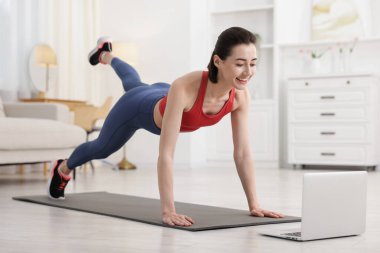 İnternetteki derste koçla tahta egzersizi yapan bir kadın. Spor ve sağlıklı yaşam tarzı