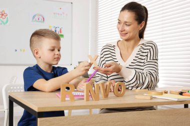 Okulda masa başında öğretmeniyle mektup öğrenen tatlı bir çocuk.