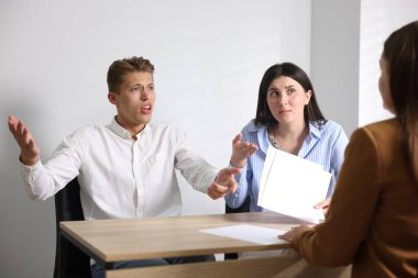 Ahşap masadaki kadına şikayet eden bir çift.