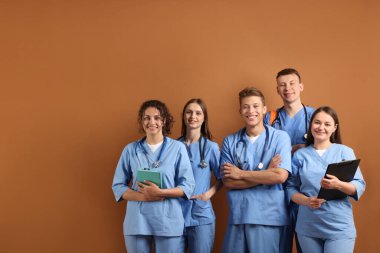 Kahverengi arka plan kitapları olan bir grup tıp öğrencisi.