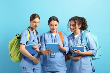 Açık mavi arkaplan üzerine kitapları olan bir grup tıp öğrencisi