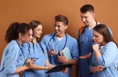 Kahverengi arka plan kitapları olan bir grup tıp öğrencisi.