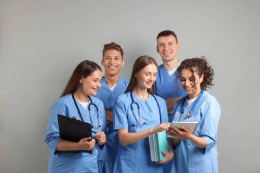 Açık gri arkaplan üzerine kitapları olan bir grup tıp öğrencisi