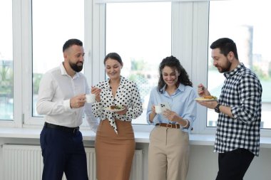 Yemek ve içeceklerle iş arkadaşları öğle arasında ofiste pencere kenarında.