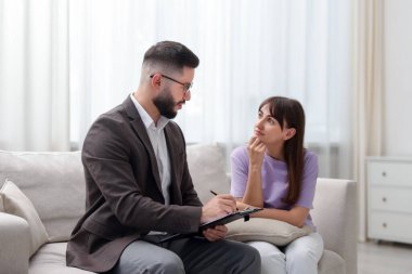 Ofisteki koltukta hastayla çalışan profesyonel psikolog.