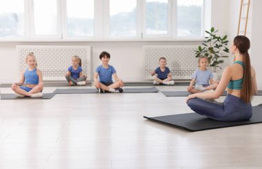 Sınıfta koçla yoga yapan bir grup çocuk.