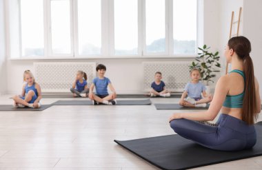 Sınıfta koçla yoga yapan bir grup çocuk.