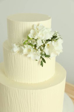 Beyaz arka planda çiçeklerle süslenmiş nefis düğün pastası, yakın plan.
