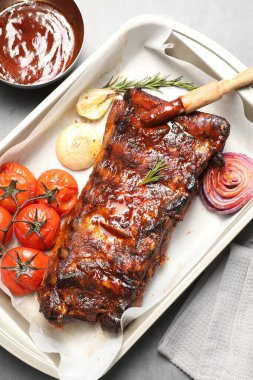 Lezzetli kaburgalar, biberiye, fırında soğan, sos ve kurutulmuş domatesler gri masada, düz yatıyordu.