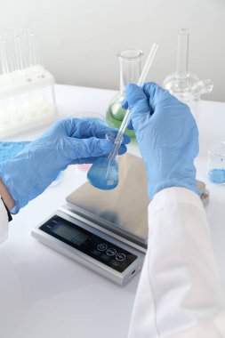 Beyaz masada numune ve ölçeklerle çalışan bilim adamı, yakın plan.