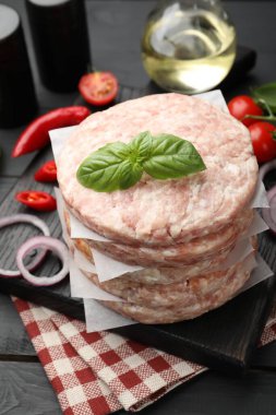 Hamburger, baharatlar ve domatesler için taze çiğ köfteler, siyah ahşap masa, yakın plan.