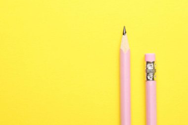 Sarı arka planda iki grafit kalem, üst manzara. Metin için boşluk