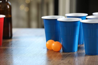 Bira pong oyunu. İçkili plastik bardaklar ve toplar ahşap masada, yakın plan. Metin için boşluk