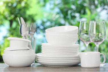 Ahşap masada, bulanık yeşil arka planda farklı temiz tabaklar.